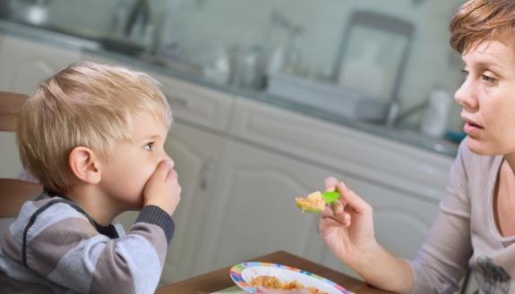 mother tries to feed fussy toddler